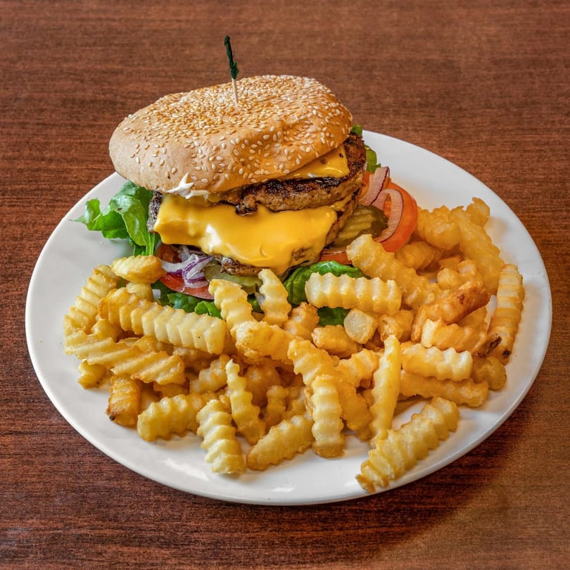 A double cheeseburger with lettuce, tomato, onion, and pickles, served with crinkle-cut fries.